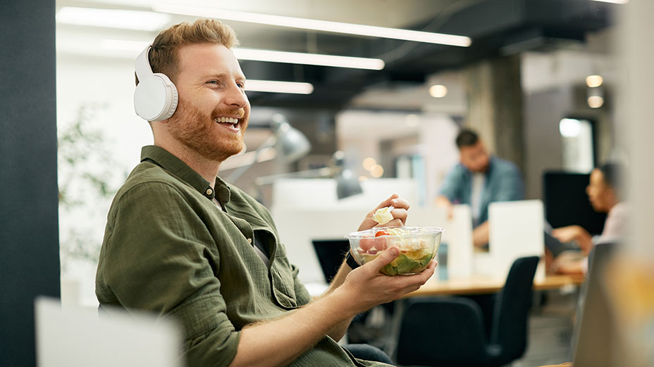 Man with headphones on smiling and eating